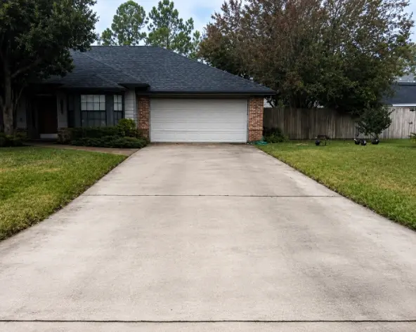Concrete driveway with one half still stained and the other cleaned to bare gray concrete