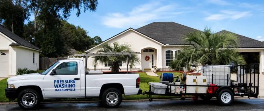 Technician soft washing the exterior siding of a two-story home